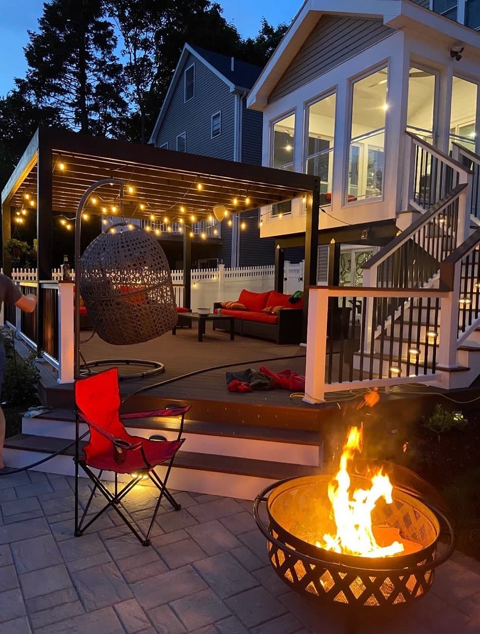 Deck with pergola, string lights and a fire pit at dusk