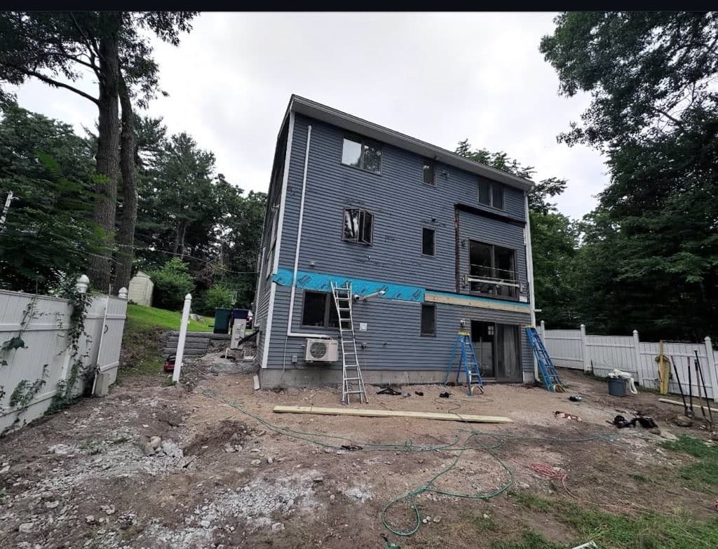 Back of a three-story house before the deck, bare graded yard
