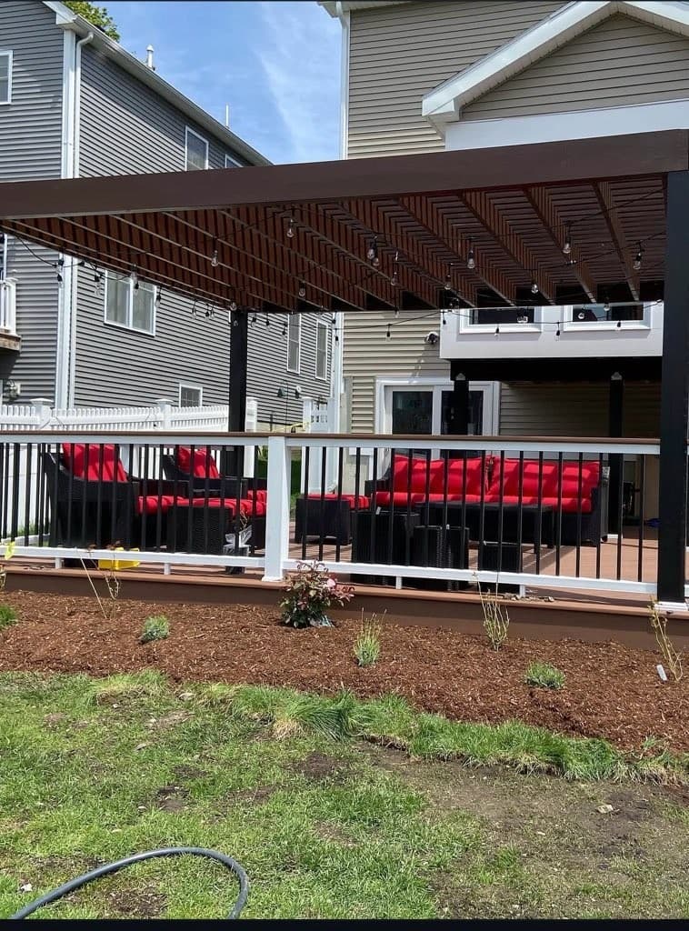 Pergola over a deck with red outdoor sectional seating and white railings