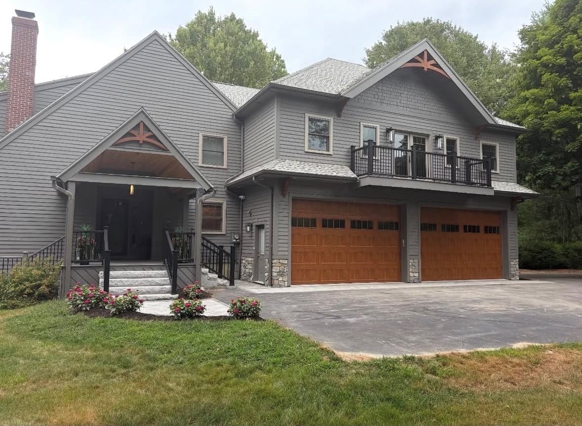 Garage addition with cedar carriage doors, a second-floor balcony and grey siding