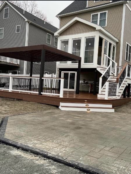 Deck with pergola and stairs to a sunroom, above a new paver patio