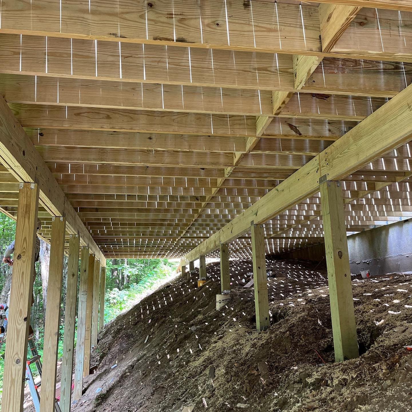 Underside of a raised deck showing posts, beams and joists