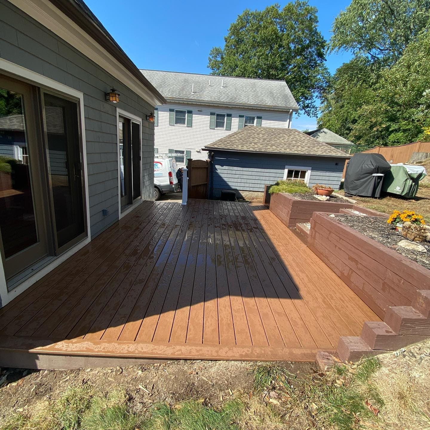 Brown composite deck wrapping around the back of a house