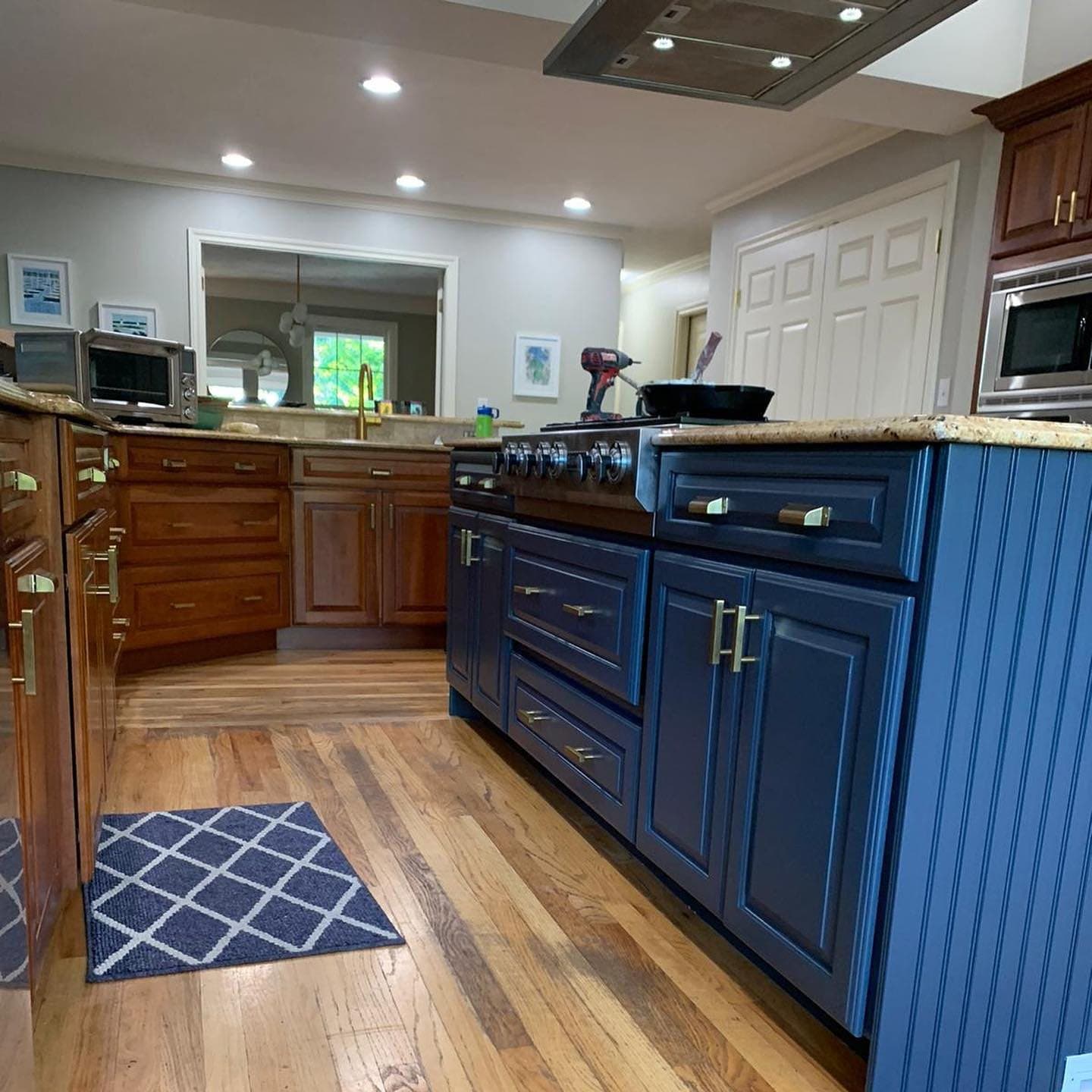 Kitchen with a navy beadboard island and hardwood floors