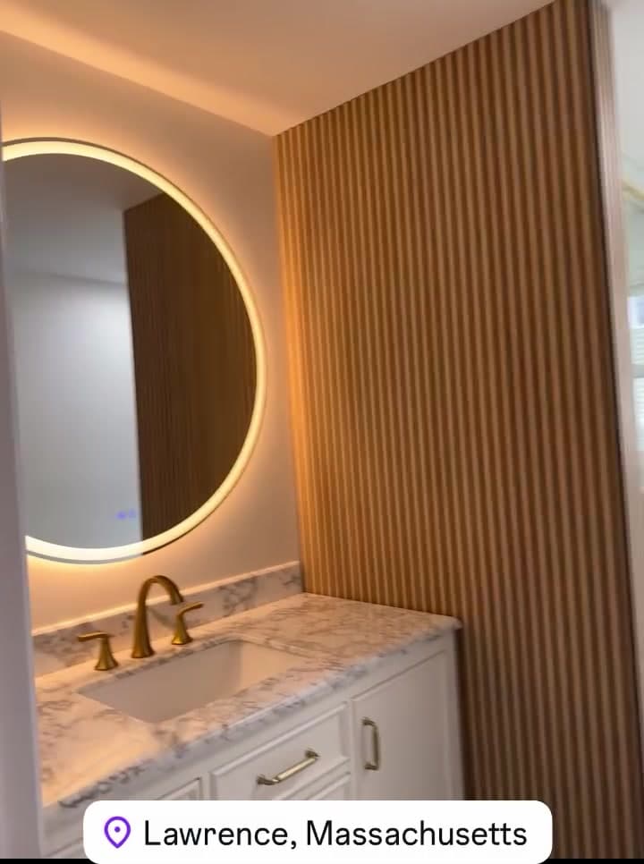 Vanity with a lit round mirror and wood slat wall