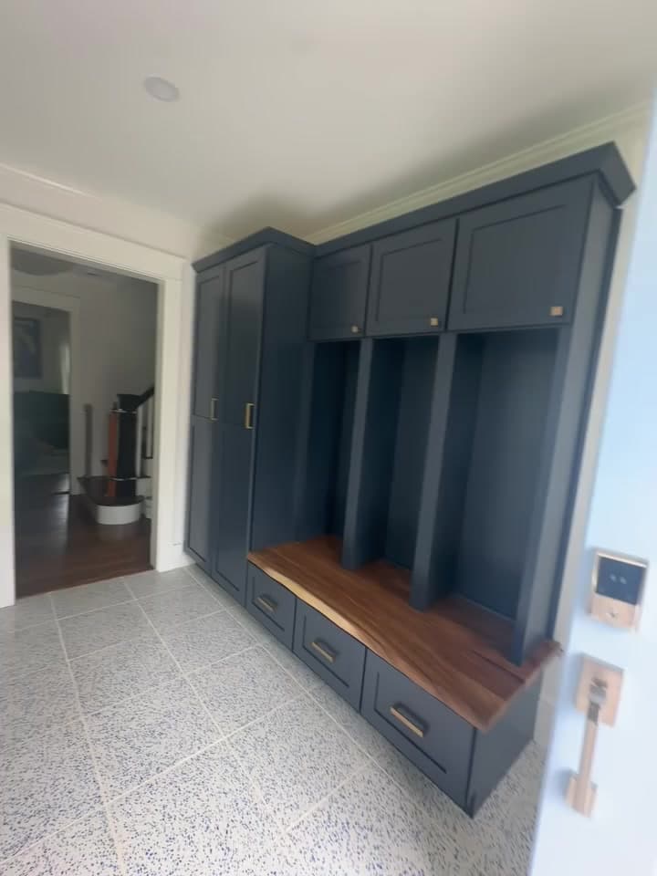 Mudroom with navy cabinets, cubbies and a wood bench over terrazzo-style tile