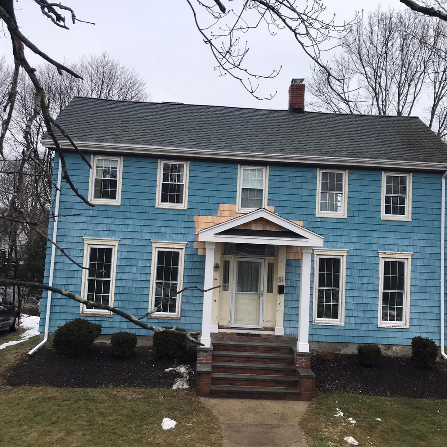 Blue colonial with new siding, white trim and a portico