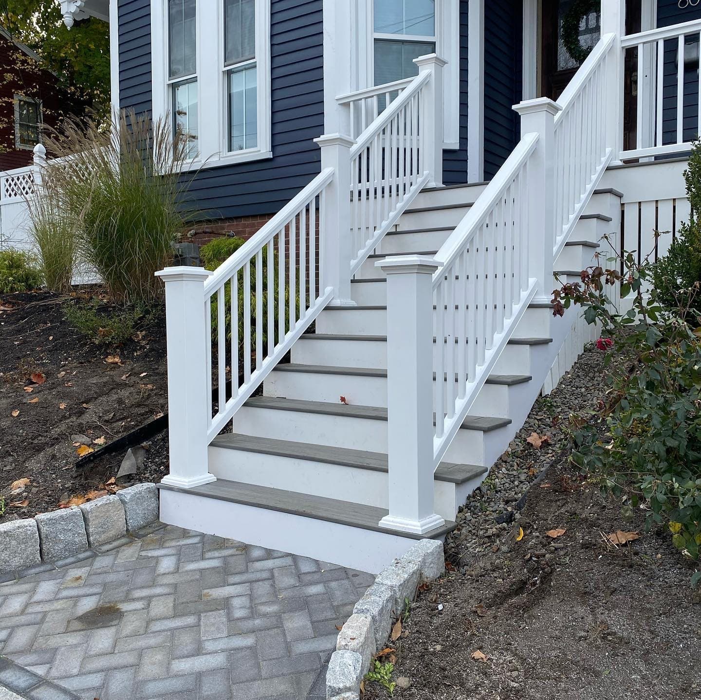 White front stairs with railings leading to a paver walkway